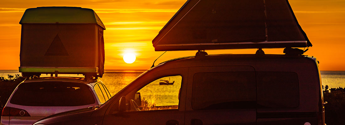 Autos mit Dachzelten bei Sonneruntergang