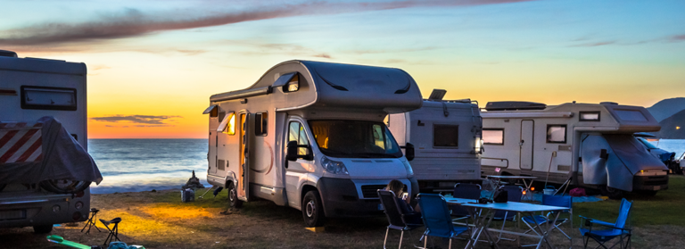 Camper und Motorhäuser mit Blick auf den Sonnenuntergang im Mittelmeer von ihrem Campingplatz am Strand, Korsika, Frankreich