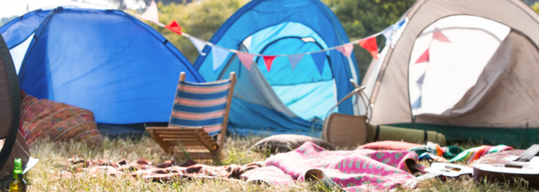 Leerer Campingplatz beim Musikfestival an sonniger Stelle. Decken liegen auf der Wiese.