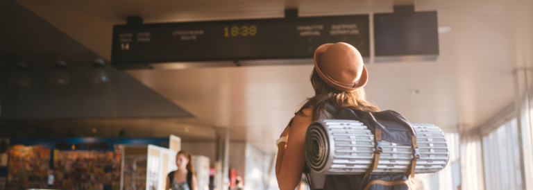 Themenreise mit öffentlichen Verkehrsmitteln. junge Frau, die sich mit Kleidung und Hut hinter Rucksack und Campingausrüstung zum Schlafen, Isoliermatte sieht nach oben.